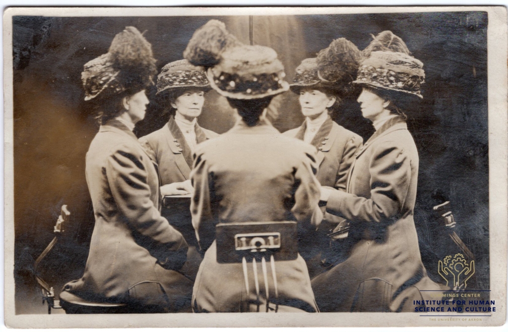 Postcard featuring a black and white image of a person in a long coat ad Victorian style hat with a large feather. The same person appears seated at a table from five different angles making it look like they are seated at a table with copies of themselves. 